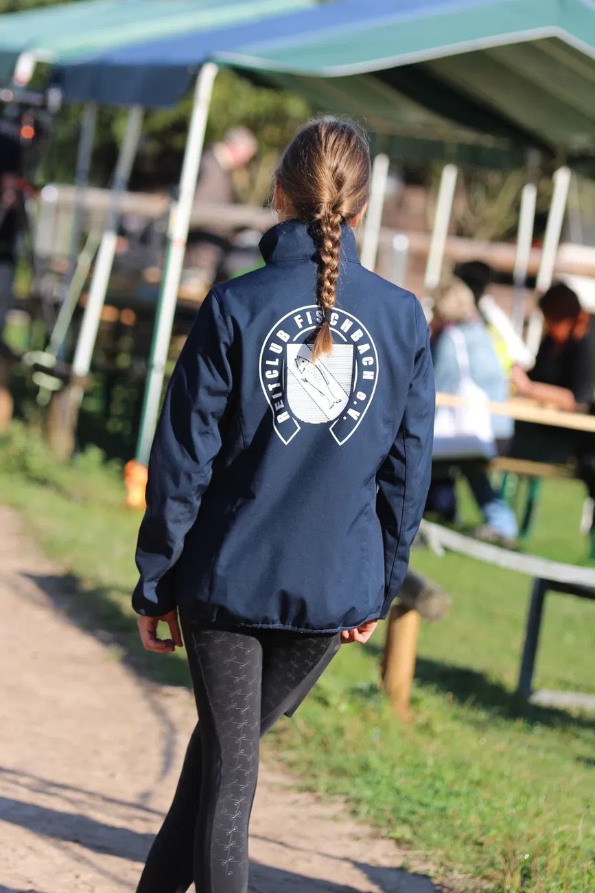 Mitglied in der marineblauen Vereinsjacke mit dem Wappen des Reitclub Fischbach auf dem Rücken